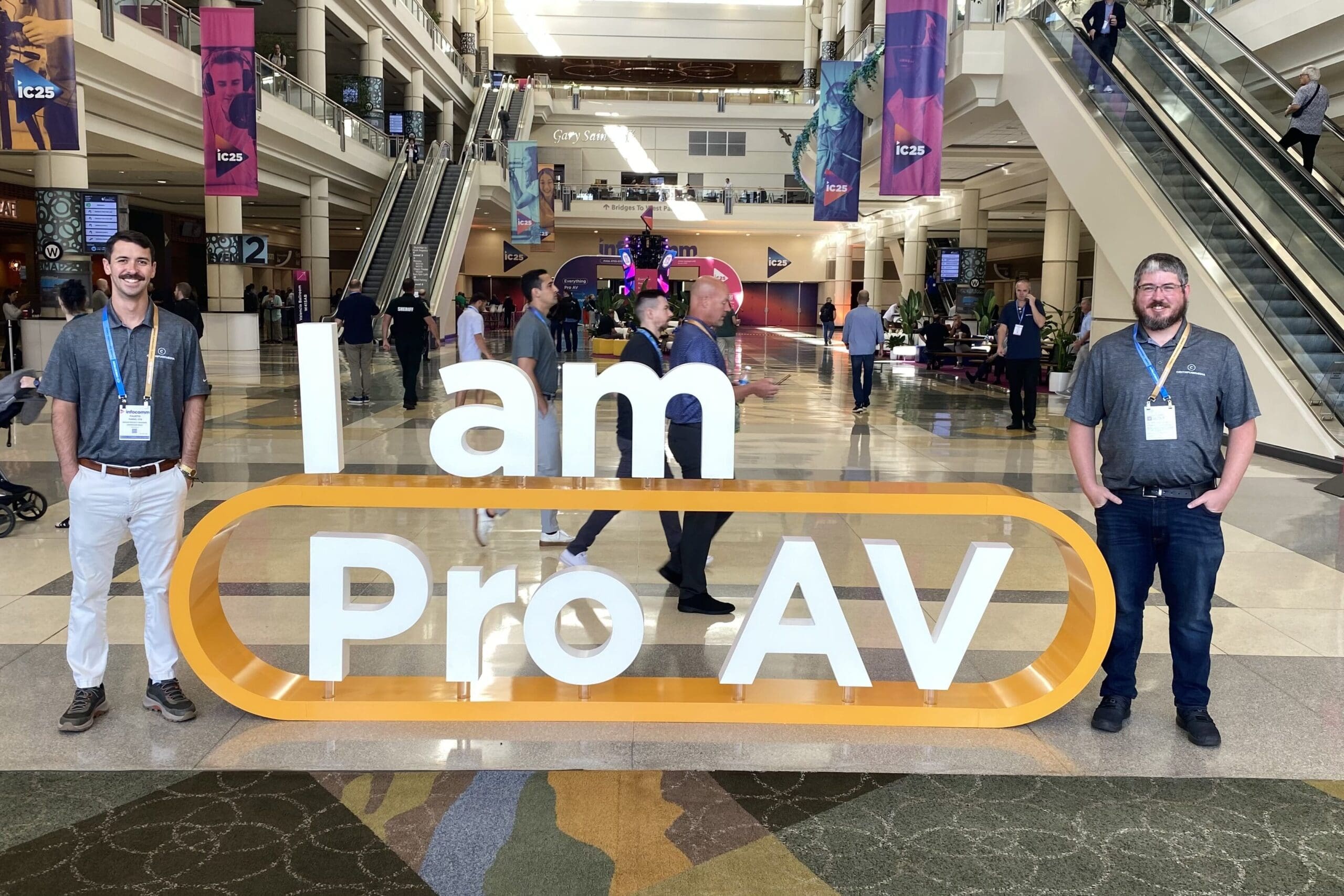 Centrifuge Media at InfoComm 2025 – Fausto Turro and Tanner Highland Standing by the sign “I am Pro AV”